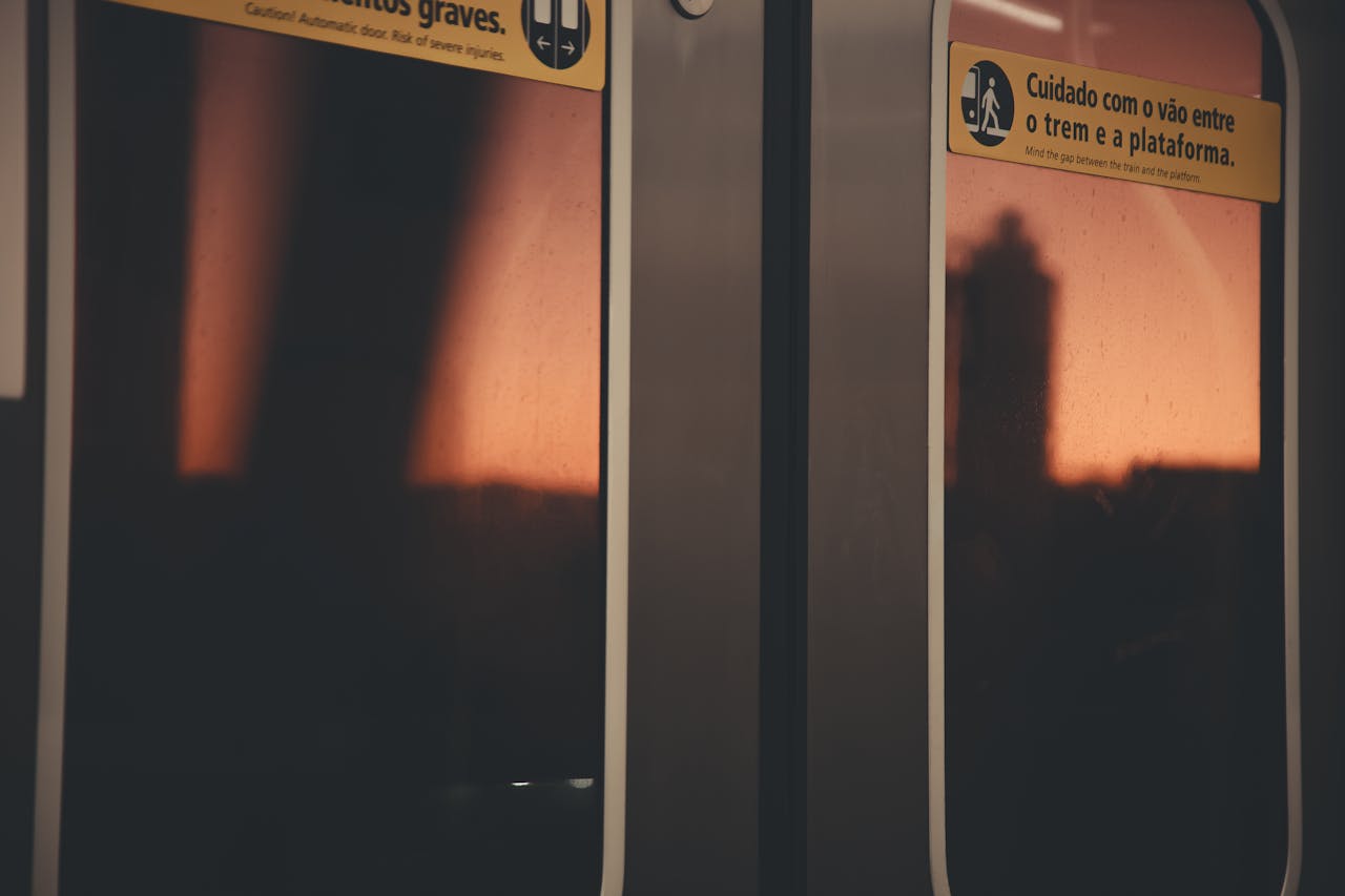 Services-01 Sunset view through a São Paulo train door window, silhouetted cityscape visible.